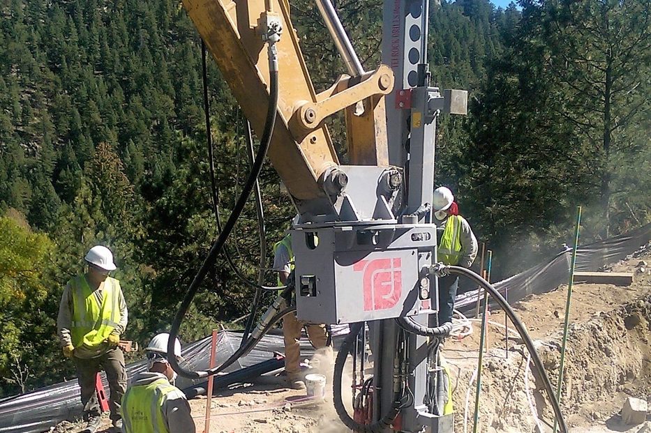Excavator and micropile drill rig working along the creek at the Crawford Gulch MSE wall