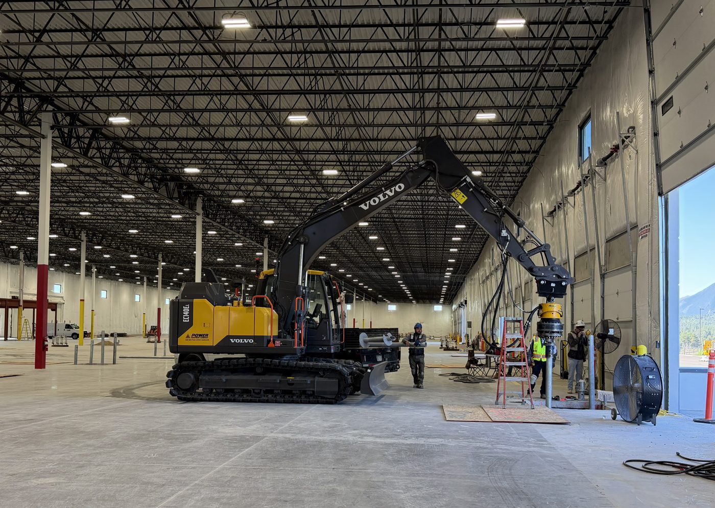 Park Range excavator installing a helical pile inside the warehouse for the Falcon Crane project