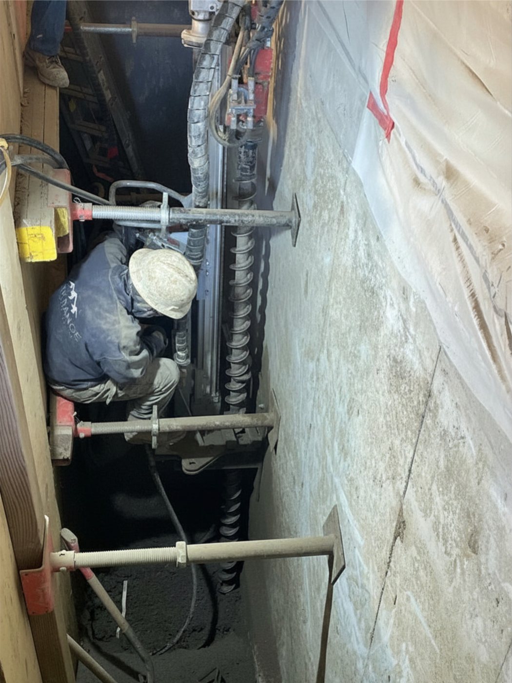 Park Range crew drilling a micropile in a tight, shored space beneath one of the townhome units